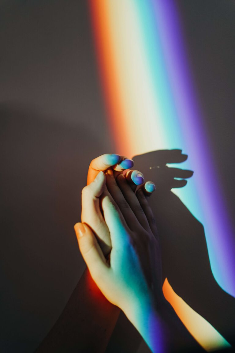 A pair of hands holding a rainbow light.