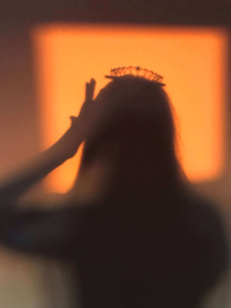 A silhouette of a woman with a crown on her head.